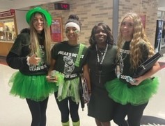 3 students and superintendent stand in hallway posing for spirit week